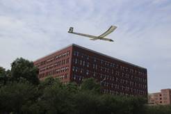 A plane flying over a buildingDescription automatically generated with medium confidence